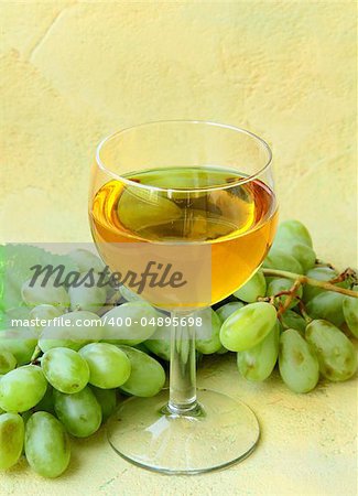 glass of white wine and a branch of green grapes