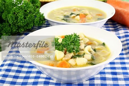 a cup of chicken soup with fresh vegetables