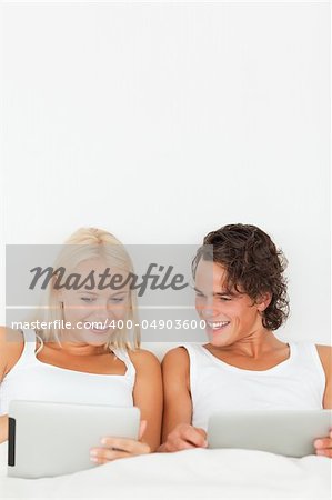 Portrait of a couple using tablet computers in their bedroom