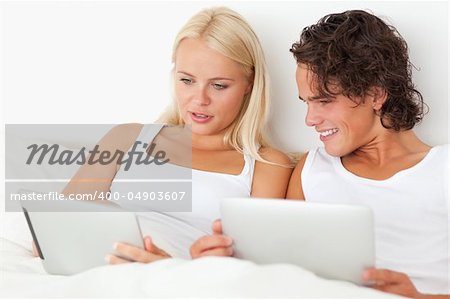 Lovely couple using tablet computers in their bedroom