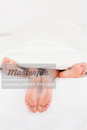 Two pairs of feet in a bed