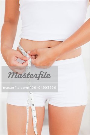 Woman measuring her belly against a white background