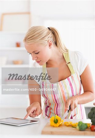 Portrait of a woman using a tablet computer to cook in her kitchen