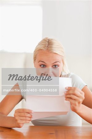 Woman looking at a letter in disbelief in her living room