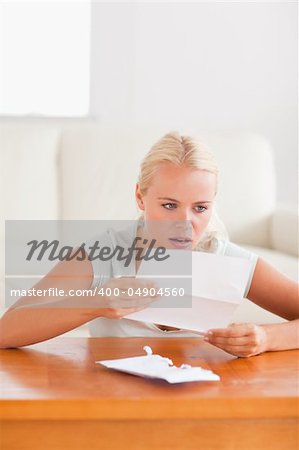 Woman looking at a letter in shock in her living room