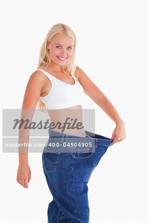 Cute woman wearing to big jeans in a studio