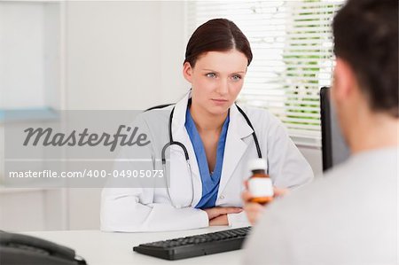 A female doctor and a patient with pills sitting in an office
