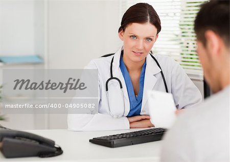 A female doctor an a patient with a prescription sitting in an office