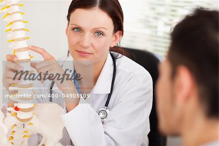 A female doctor is showing a patient a spine