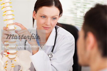 A female doctor is showing her patient a spine