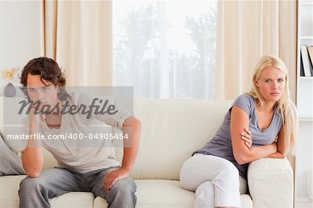 Sorrowful couple sitting on a sofa not looking at each other