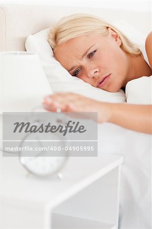 Portrait of a woman awaken by an alarmclock  in her bedroom