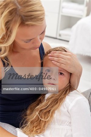 Sick little girl sitting in her mother's lap being comforted