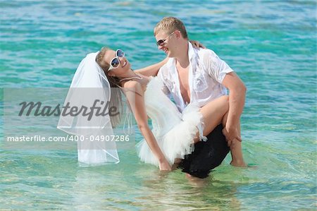 Groom holding up a bride on the beach