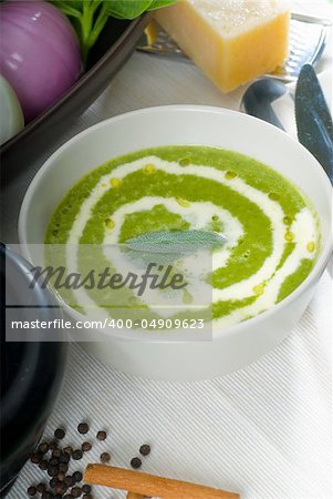 fresh spinach soup on a white bowl with sage and cream on top