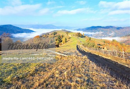 Autumn misty morning plateau with stack of hay and country dirty road (Mighgirya village outskirts, Carpathian Mt's, Ukraine).