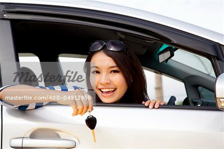 young happy woman in car showing the key