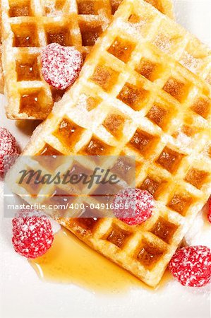 sugar covered raspberries on waffles with syrup from top on white background