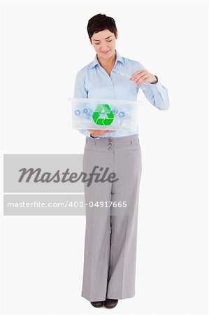 Woman putting an empty plastic bottle in a recycling box against a white background