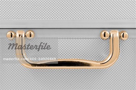 Golden handle detail of an aluminum case.