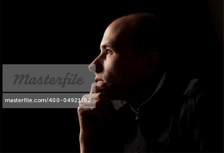 Portrait of young man thinking, black background