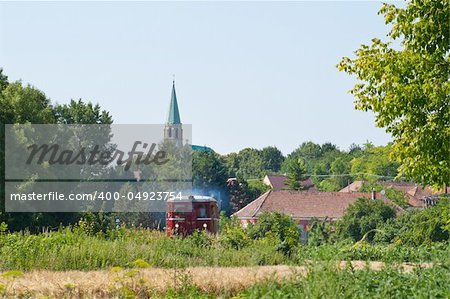 little red train passing through the village and the countryside