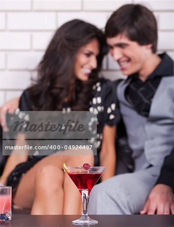Couple in background on date in bar or night club with wine glass in focus.