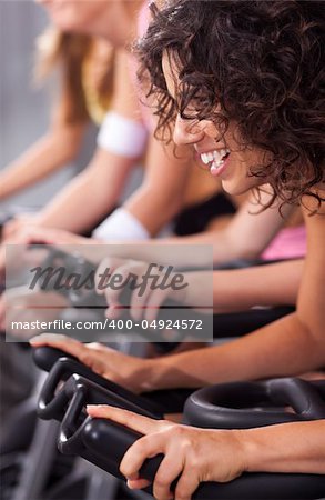 Four people on bicycles in a gym or fitness club for a workout.