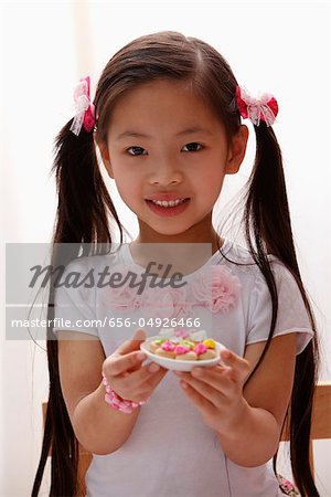 young girl with pony tails holding cookies