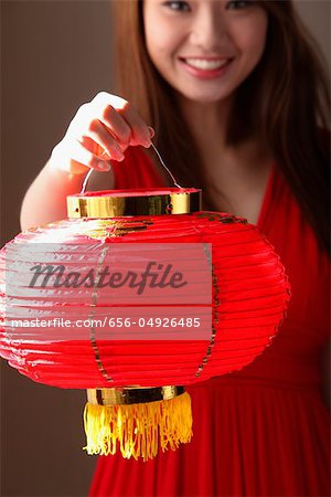 Jeune femme tenant une lanterne rouge et souriant