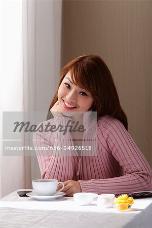 Jeune femme assise dans le café près de fenêtre