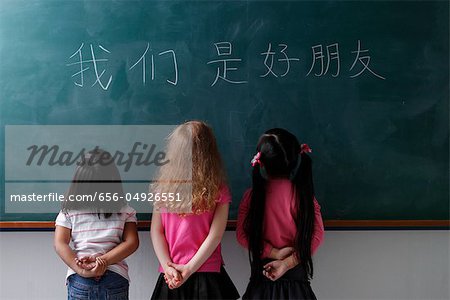 three young girls looking at Chinese characters "We are all friends"