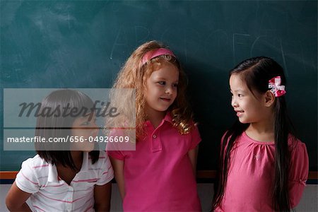 three young girls smiling at each other
