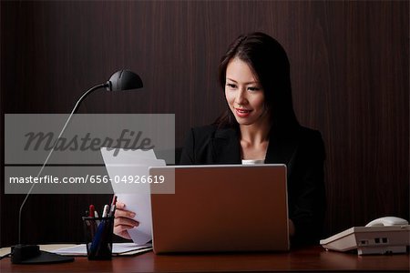 Chinesische Frau sitzend am Schreibtisch Blick auf Papier