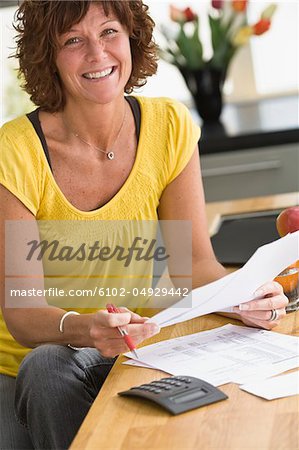 Woman sitting with bills, smiling