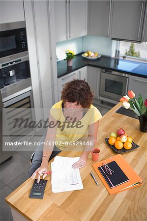 Femme assise et calcul en cuisine