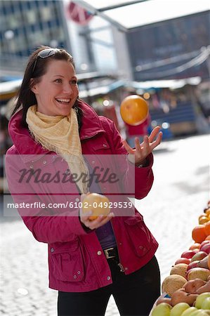 Young woman juggling with fresh oranges