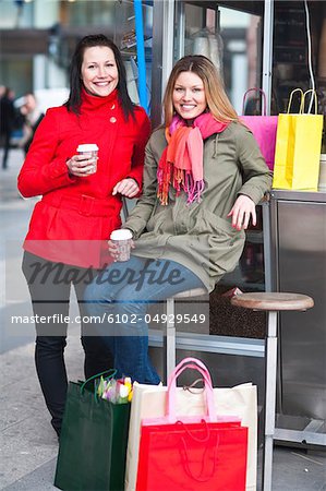 Paire de jeunes femmes prenant pause shopping, boire du café à emporter