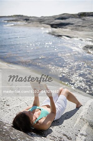 Livre de lecture de femme sur rocher