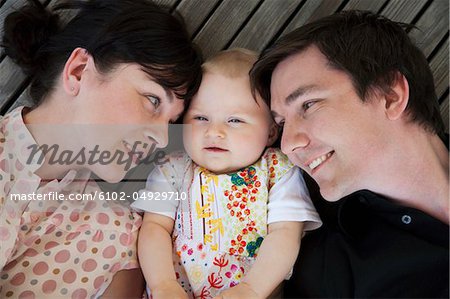 Baby girl lying between father and mother