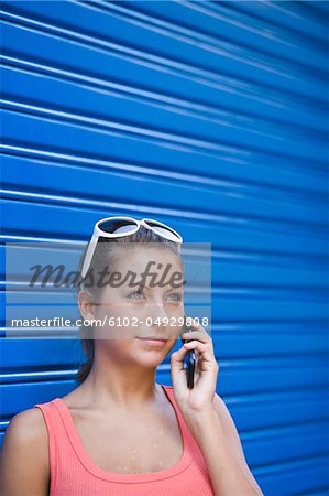 Young woman in front of blue wall, talking on phone