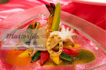 Roasted zucchini and peppers topped with a variety of seafood and a polenta spire