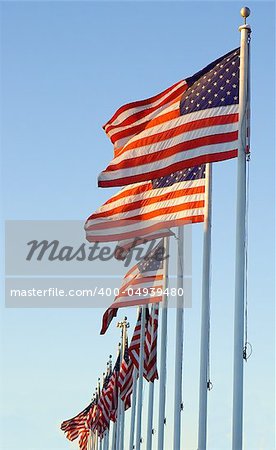 A line of American flags against a bright blue sky.