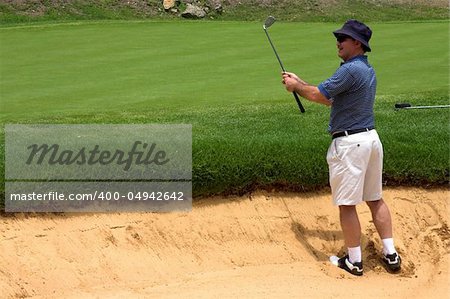 Golfer in the sand bunker. Happy because he landed the ball right next to the hole.