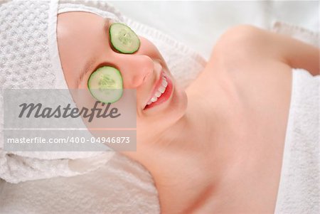 Woman laying on towel with cucumbers on her eyes