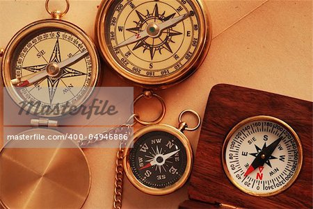 Four antique compasses over old map background