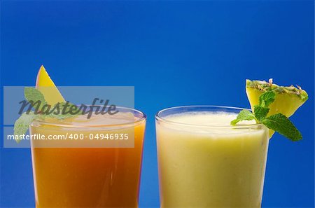 Mango papaya and pineapple banana smoothie against blue background