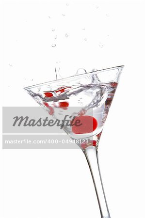 Two red cherrys splashing into a cocktail glass
