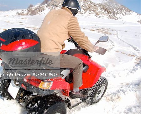 Man riding quad in mountain snow