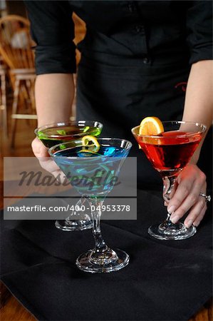 three colorful alcoholic drinks are prepared and served